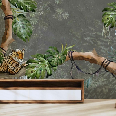 A living room wall mural features two leopards among lush green foliage and tree branches against a muted gray background. The wallpaper combines vibrant greens with neutral tones, showcasing detailed wildlife imagery and natural elements seamlessly.