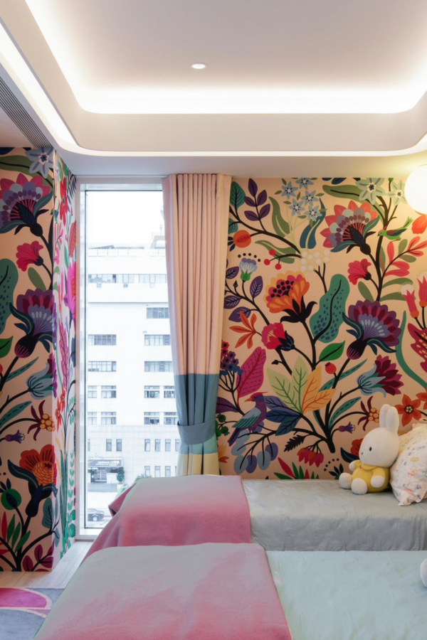 Brightly decorated bedroom with colorful floral murals on the walls. The wallpaper features vibrant flowers in shades of pink, teal, and gray.