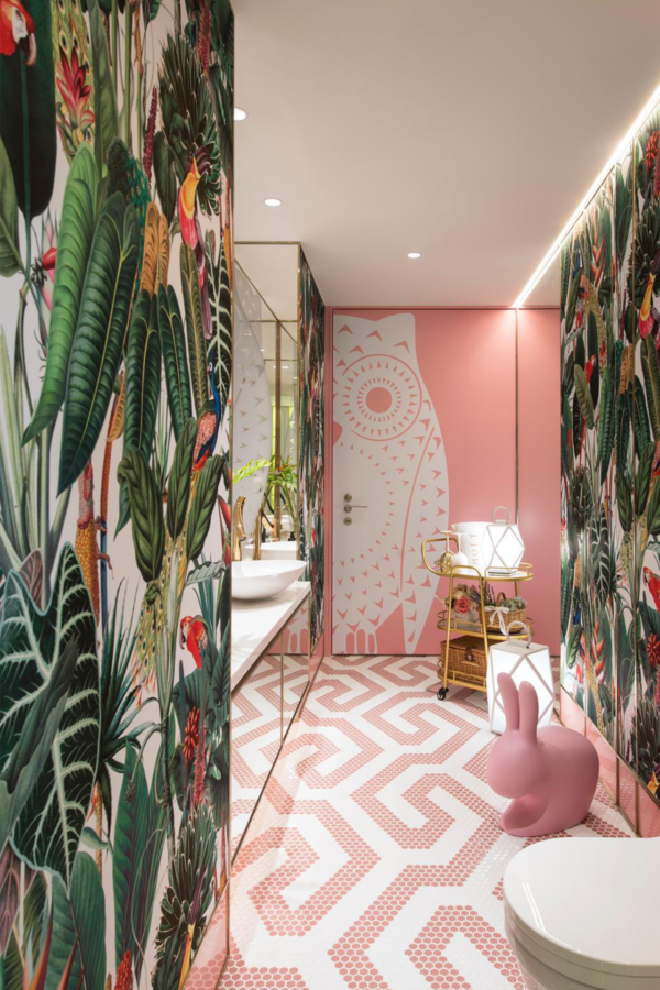The wallpaper features a vibrant tropical theme with large green leaves and colorful birds. The elaborate design showcases various shades of green, bright pinks, deep blues, sunny yellows, and hints of orange. Birds depicted include parrots and toucans with striking plumage. This rich blend of colors and elements creates a lush jungle-like backdrop for the bathroom.