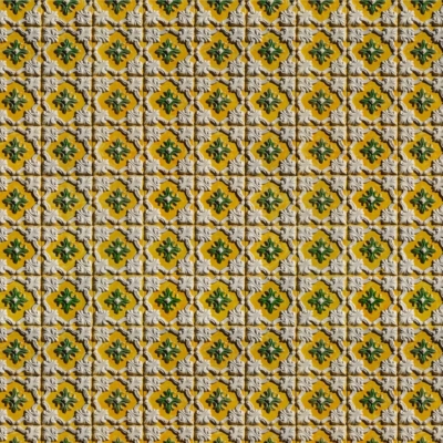 Intricate wallpaper pattern with small, repetitive floral designs on each tile. Yellow background, green and orange accents, bordered by raised white grout. Symmetrical and textured surface designed to bring a 