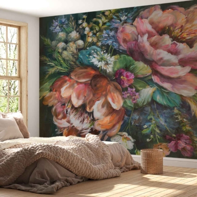 A large, colorful floral mural adorns the wall, featuring vibrant blooms in hues of red, pink, blue, and yellow. Green leafy accents intertwine among the flowers. The background is a soft cream color, enhancing the richness of the floral patterns. This lively wallpaper brings nature indoors with its bold yet elegant design.