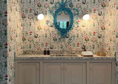 The bathroom features floral wallpaper with vibrant blooms in shades of red, pink, and orange, along with green leaves. The background is a soft cream color interwoven with subtle golden accents enhancing the floral pattern.