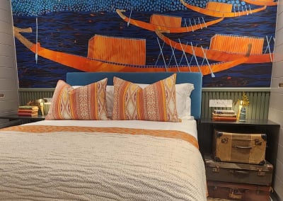 A vibrant mural wallpaper features orange boats on blue water with a red sun.