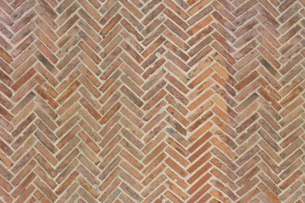 Create a Herringbone brick wall with alternating shades of brown and orange bricks. Enhance the V-shaped, zigzag pattern using shadow lines and maintain visible mortar lines for added depth. Highlight key elements: **Herringbone pattern**, **alternating shades of brown and orange**, **V-shaped zigzag** design, and **shadow lines with visible mortar lines** for a visually appealing geometric wallpaper.
