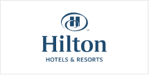 The wallpaper features a repeating pattern of a stylized "H" encircled, reminiscent of elegance and home. Dominated by bold blue hues, the elements create an inviting ambiance. The background includes subtle horizontal lines, enhancing the formal yet welcoming design. Look for deep blue colors and circular patterns when searching.