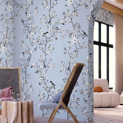 The wallpaper features a vibrant design with intricate floral patterns and delicate birds perched among the branches. The colors include lush greens, soft pinks, deep blues, and subtle yellows, set against an off-white background. The detailed illustrations capture a sense of nature's beauty with blooming flowers and graceful birds in flight, adding elegance and a touch of whimsy to any room. Perfect for an interior seeking a harmonious blend of nature-inspired elements.