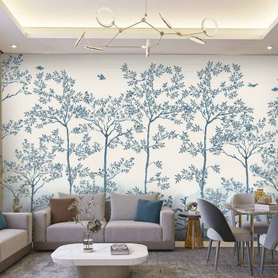 The mural wallpaper features stylized trees and birds. The design includes elements like elongated tree trunks, abstract branches, and minimalistic bird shapes. Color palette highlights include earthy greens, soft blues, muted browns, and touches of gold. The background is a gentle cream or off-white tone, balancing the overall aesthetic with subtle sophistication.