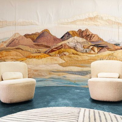 The wallpaper features a tapestry mural of mountains with warm hues, such as orange, red, and gold. It highlights natural and earthy elements, creating an artistic backdrop.