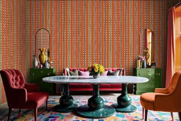 Colorful vertical stripe-patterned wallpaper featuring vibrant hues such as reds, oranges, pinks, and greens. The design is eclectic and bold, complementing the lively atmosphere of the room.