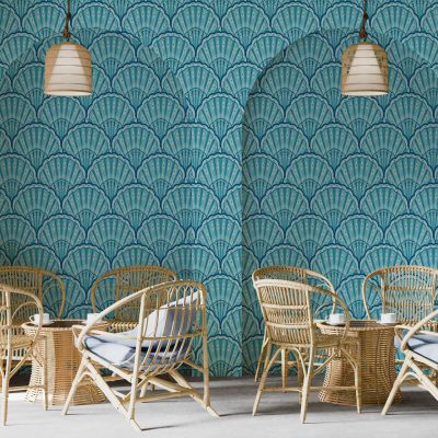 Blue scallop-patterned wallpaper with Memphis-inspired design; features rounded, repetitive wave-like shapes in various shades of blue, accented by graphic motifs and playful geometric elements in contrasting colors such as white, pastel pinks, and yellows.