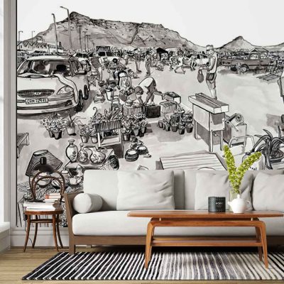 Black and white wall mural featuring a detailed busy outdoor market scene; includes people, cars, street vendors, tents, and distant mountains. The artwork is monochromatic with high-contrast black ink linework and shading on a white background.