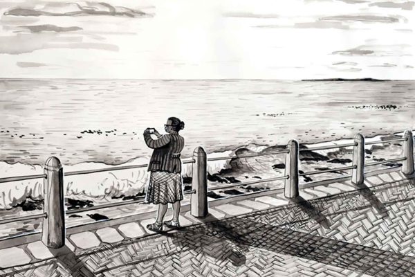 Wallpaper features: seaside promenade, person seen from behind, holding phone/camera, facing ocean. Foreground: walkway/railing. Background: gently crashing waves, light clouds in sky. Colors: blues (ocean/sky), pastel/orange tints (clouds/sunset glare), muted walkway tones.