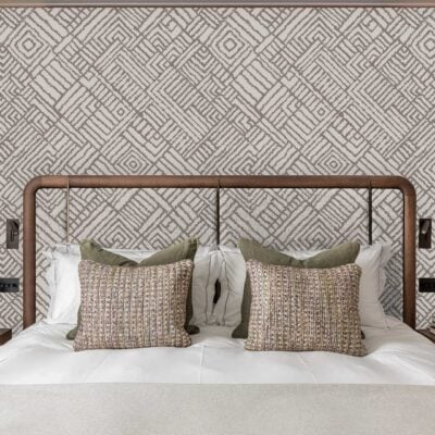 Geometric patterned wallpaper featuring interlocking shapes in shades of gray and white creates a bold backdrop behind the bed. The repeating motif stands out, adding visual interest and a modern touch to the room's decor.